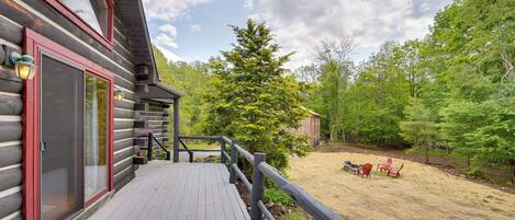 A wooden deck with a railing, a door, and a small outdoor seating area with chairs.