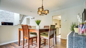 Un coin repas avec une table et des chaises en bois, un lustre et une plante.