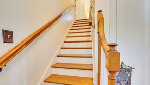 Un escalier en bois, doté d’une rampe et d’une pancarte de bienvenue accrochée au mur.