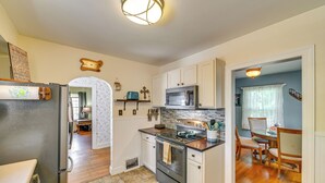 Une cuisine équipée d’un réfrigérateur, d’une cuisinière, d’un four à micro-ondes et de meubles de rangement en bois. On y trouve également un coin repas avec une table et des chaises.