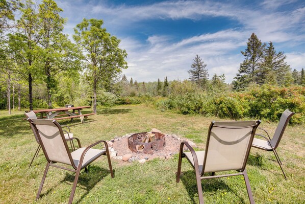 An outdoor seating area with two chairs and a fire pit surrounded by a natural landscape.