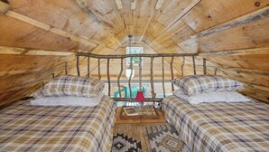 Quarto de sótão aconchegante com duas camas, teto de madeira e vista para o exterior.