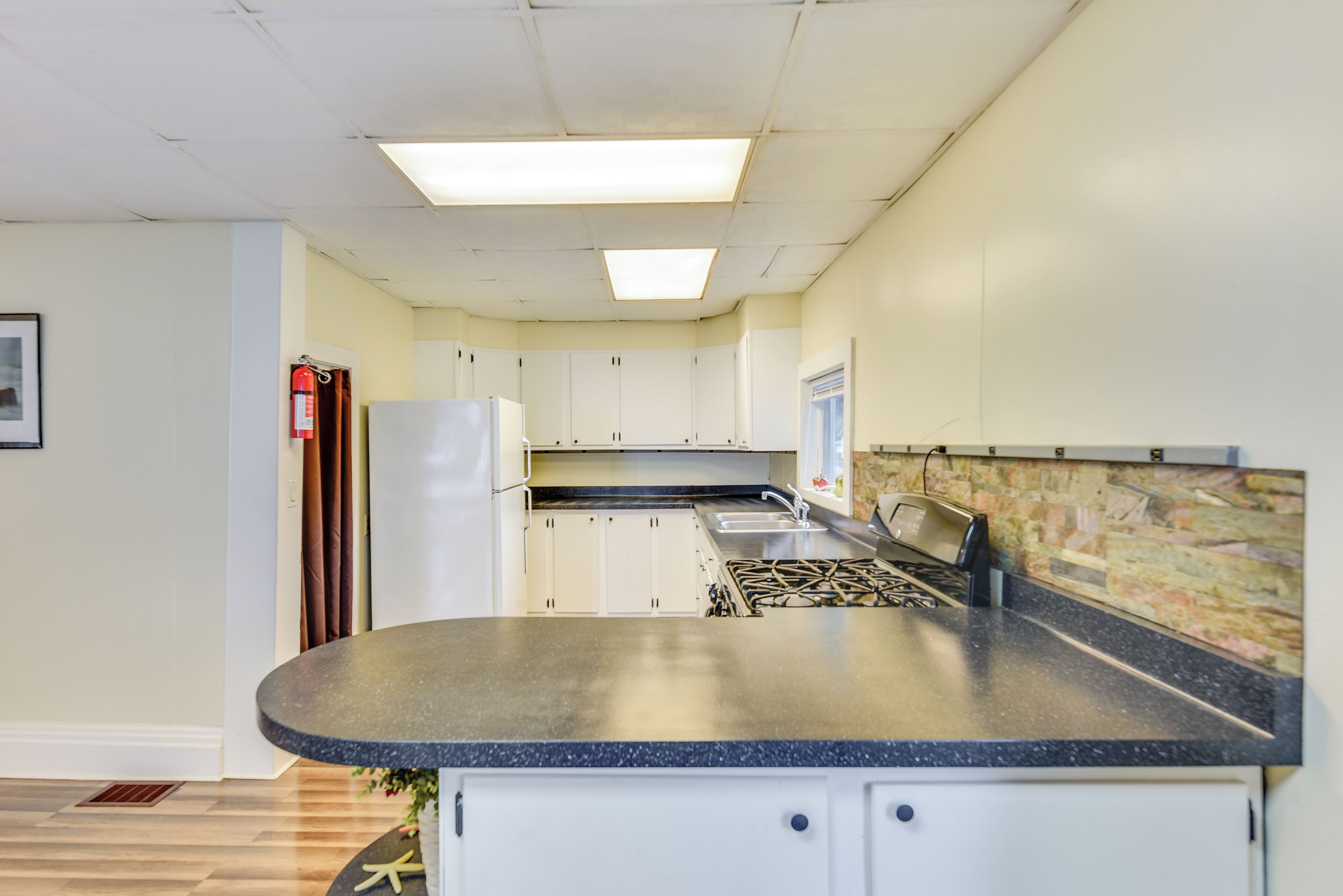 A kitchen with white cabinets, a gas stove, a sink, and a refrigerator.