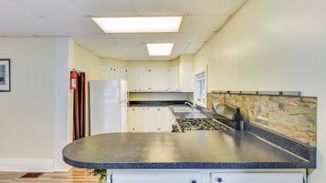 A kitchen with white cabinets, a gas stove, a sink, and a refrigerator.