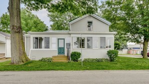 Ein eingeschossiges Haus mit grüner Tür, einer kleinen Veranda und einem Rasen.