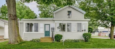 A single-story house with a green door, a small front porch, and a lawn.