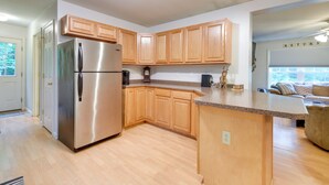 Una cocina moderna con armarios de madera, un refrigerador de acero inoxidable y una encimera de granito.