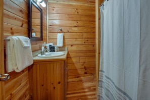 Ein Badezimmer aus Holz mit Waschbecken, Spiegel und Handtuchhalter.