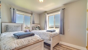 A bedroom with two beds, large windows, and a view of the outdoors. - Bright Wyoming Retreat w/ Deck & Mountain Views! (Saratoga)