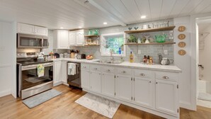 A modern kitchen with white cabinetry, stainless steel appliances, and a window with a view of greenery. - Charming Manheim Cottage w/ On-site Animal Viewing (Manheim)
