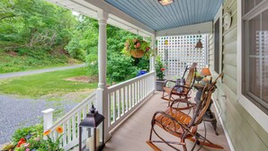 A porch with white railings, rocking chairs, a hanging planter with flowers, and a lantern. - Charming Manheim Cottage w/ On-site Animal Viewing (Manheim)