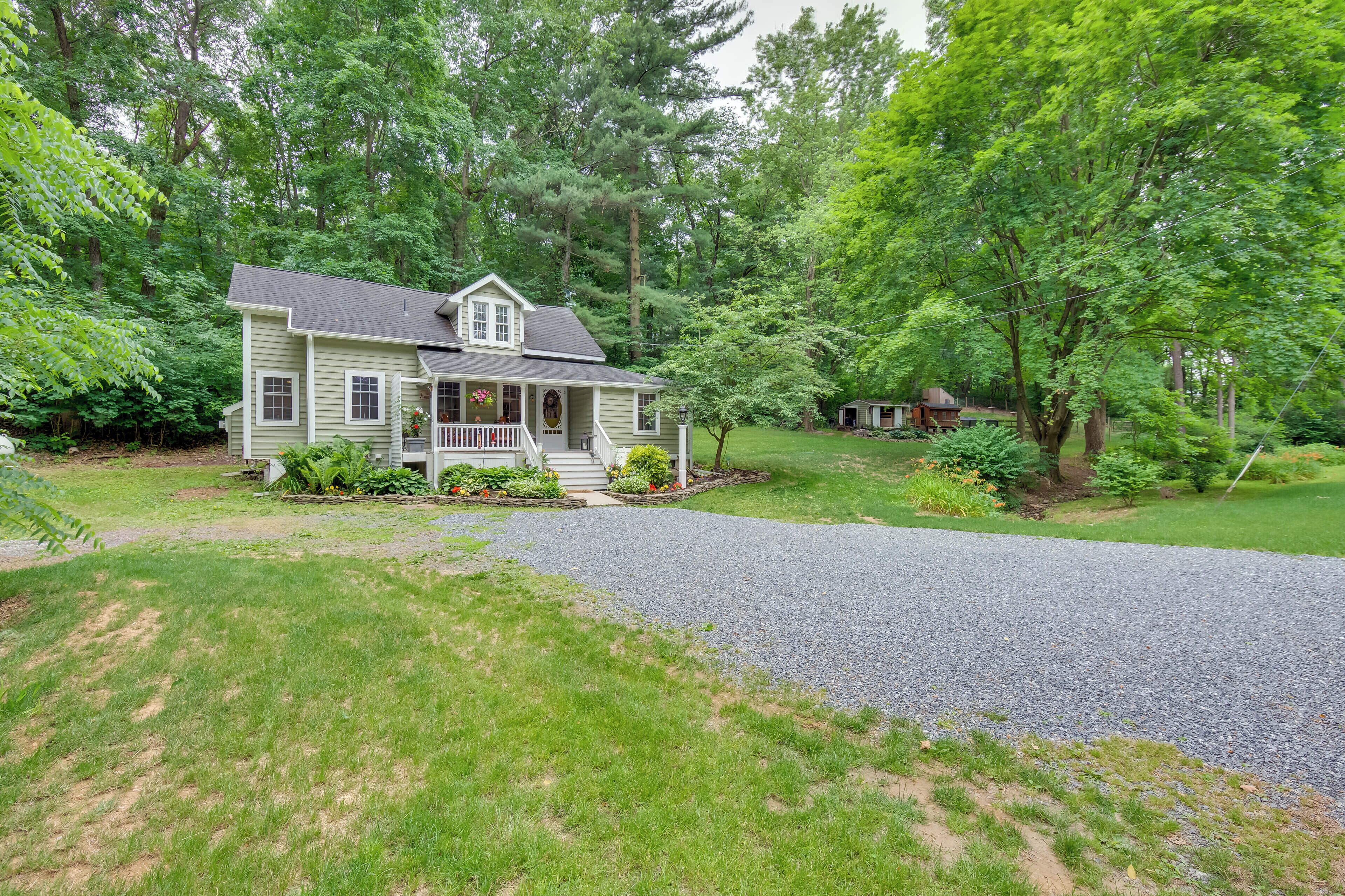 A two-story house with a front porch, surrounded by a well-maintained lawn and trees.