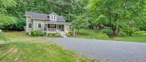 A two-story house with a front porch, surrounded by a well-maintained lawn and trees.