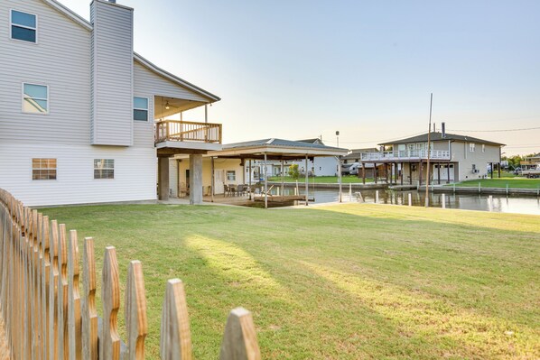 A residential property with a large lawn, a wooden deck, and a small dock by a body of water.