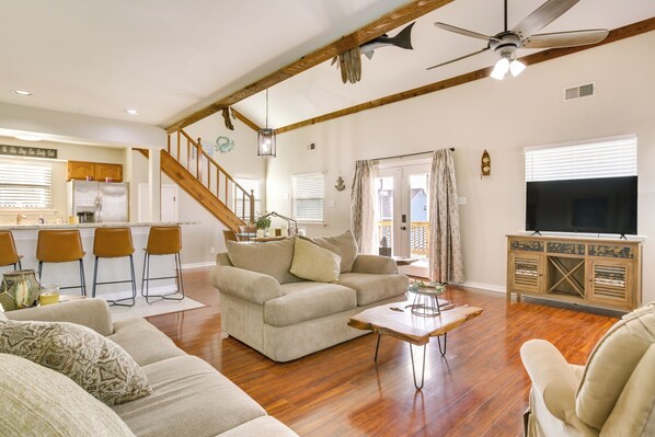 A spacious living area with a wooden ceiling, a sofa, a coffee table, and a television. - Bayou Bliss: Barataria Waterfront Getaway w/ Dock! (Barataria)
