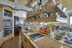 Una cucina moderna con elettrodomestici in acciaio inox, piani di lavoro in granito e diversi utensili da cucina sugli scaffali.