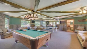 Una mesa de billar en una habitación con techo alto, vigas de madera y una mesa de pool.