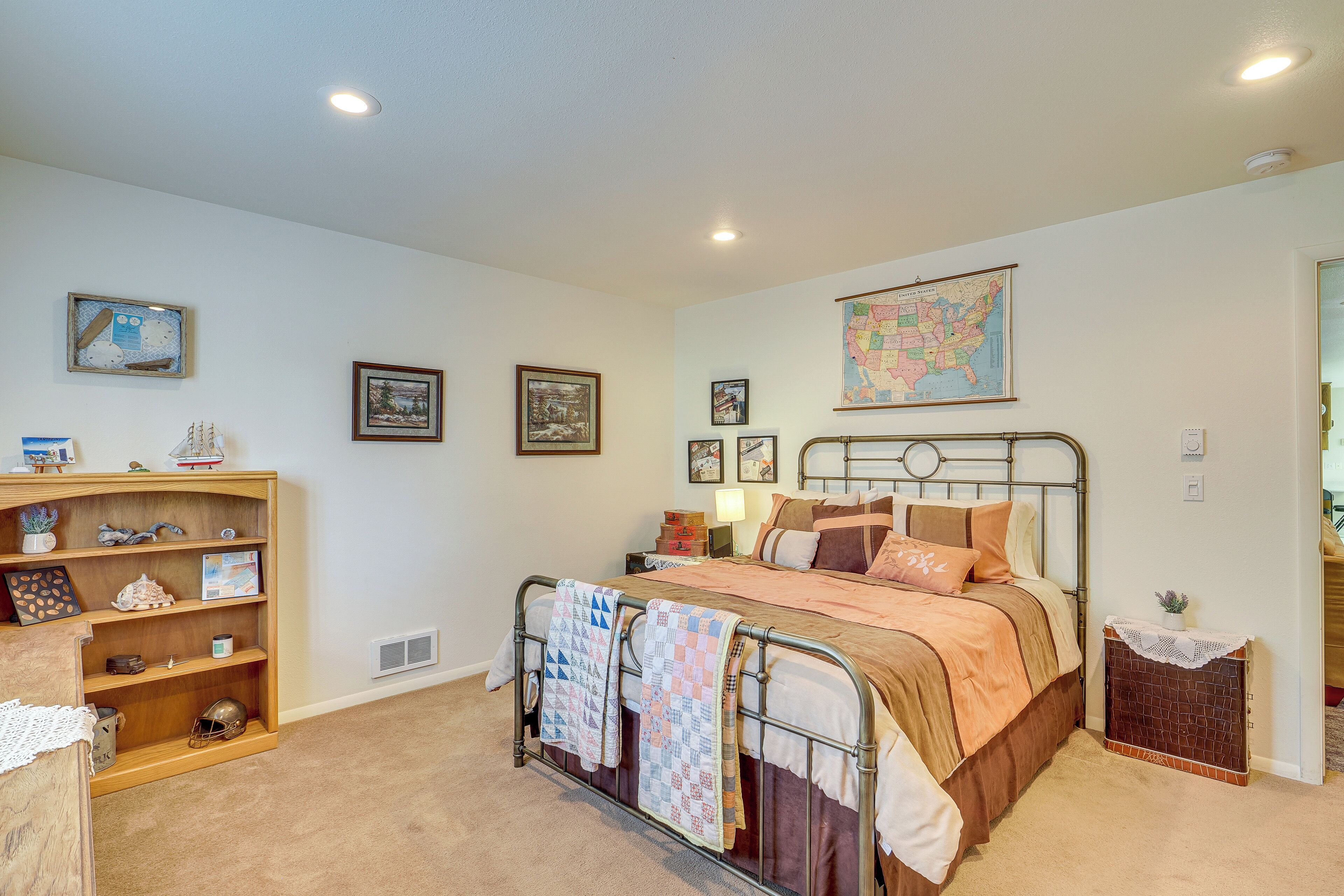 Un dormitorio con estructura de cama metálica, estante de madera y un mapa en la pared.