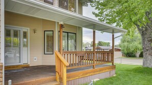 A house with a wooden porch, a front door, and a large tree in the yard. - Charming Elko Home w/ Pool Table! (Elko)