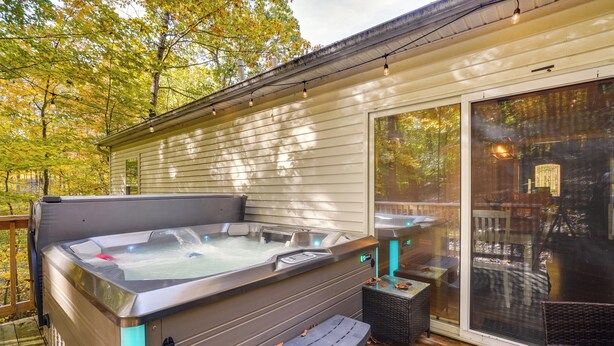 Un jacuzzi en una terraza de madera con una puerta de vidrio que da a un patio.