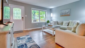 Una sala de estar con un sofá color beige, una mesa de centro blanca y una alfombra azul estampada.