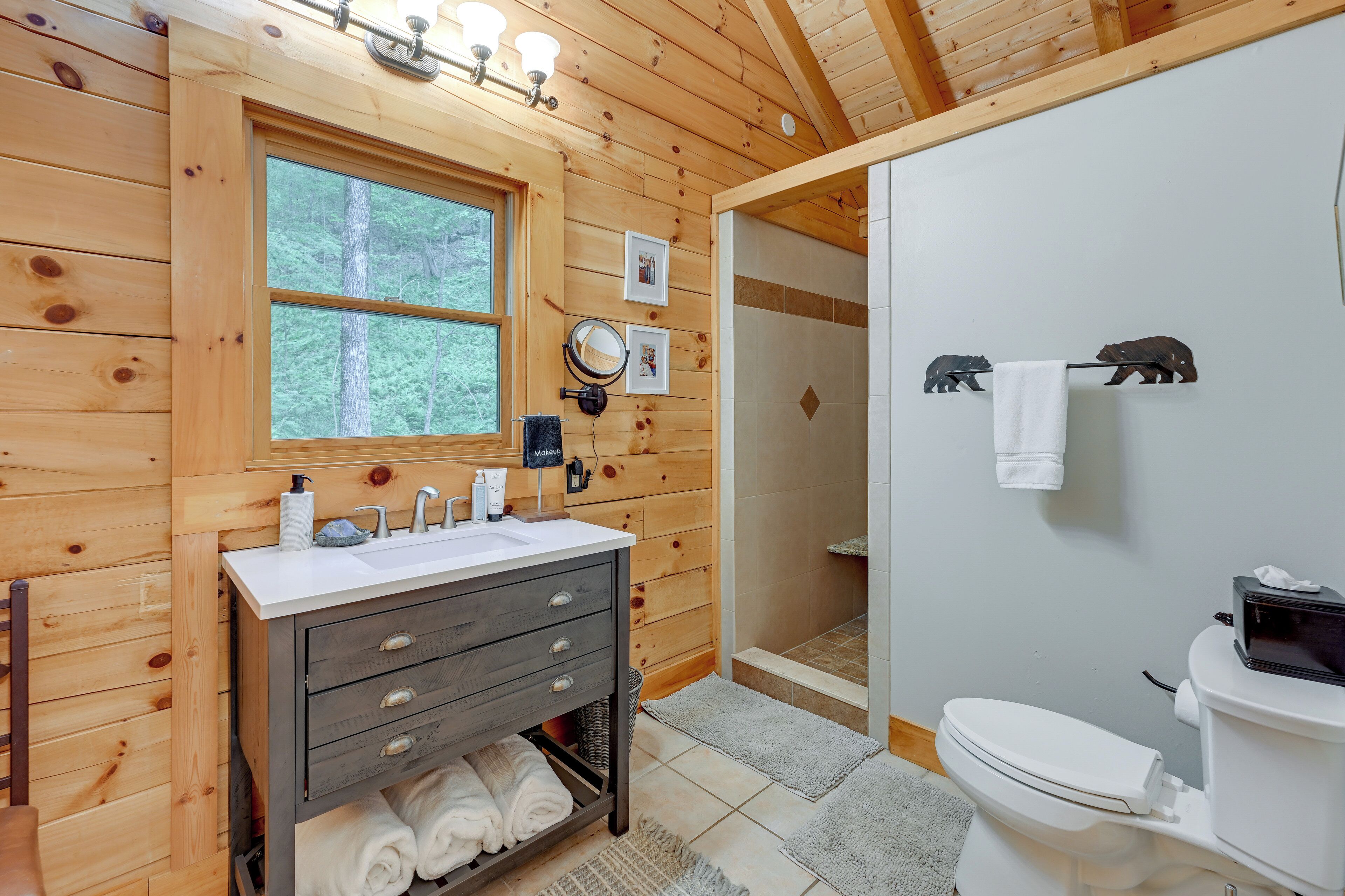 A wooden cabin bathroom with a sink, mirror, and toilet.