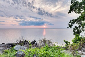 A coastal landscape with a sunset over the water, rocks, and greenery. - Multi-level Bonneau Cabin: Walk to Lake! (Bonneau)