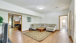A spacious living room with a wooden floor, a beige sofa, a coffee table, and a television on a stand. - Peaceful Pineville Vacation Rental w/ Grill! (Pineville)