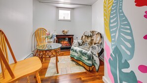 A cozy living room with a fireplace, a dining table with chairs, and a large wall mural. - East Hartford Studio ~ 4 Mi to Downtown Hartford! (East Hartford)