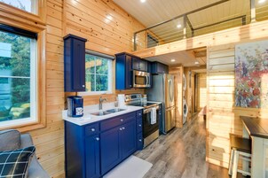Una cocina moderna con paredes de madera, un refrigerador de acero inoxidable y un microondas.