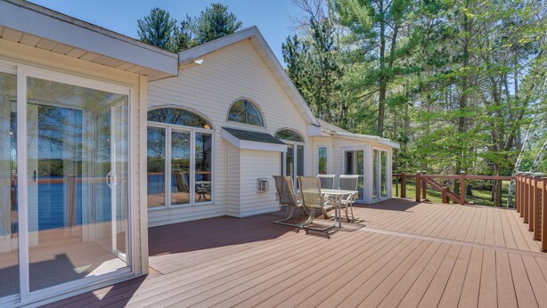 Une terrasse en bois avec une porte vitrée donnant sur un patio abrité.