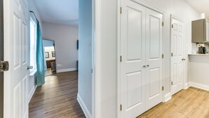 A hallway with white doors, wooden flooring, and a blue wall. - Texas Family Home w/ Hot Tub: 1 Mi to Lake Whitney (Whitney)