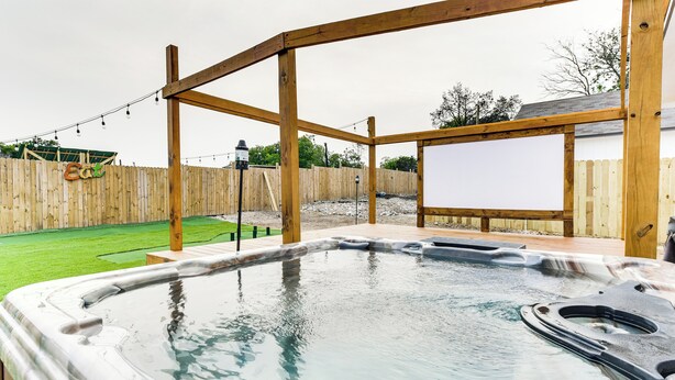 A hot tub with a wooden deck structure, surrounded by a wooden fence and a grassy lawn. - Texas Family Home w/ Hot Tub: 1 Mi to Lake Whitney (Whitney)