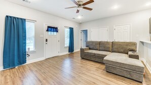 A spacious living room with hardwood flooring, a sectional sofa, a ceiling fan, and a door with a window. - Texas Family Home w/ Hot Tub: 1 Mi to Lake Whitney (Whitney)