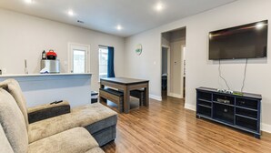 A living room with a sofa, a coffee table, a TV, and a wooden floor. - Texas Family Home w/ Hot Tub: 1 Mi to Lake Whitney (Whitney)
