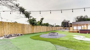 A backyard with a wooden fence, a fire pit, and a small wooden structure. - Texas Family Home w/ Hot Tub: 1 Mi to Lake Whitney (Whitney)
