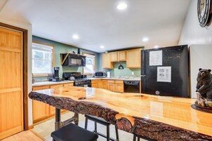 Una cocina con armarios de madera, encimera de granito, refrigerador negro y una estatua de oso.