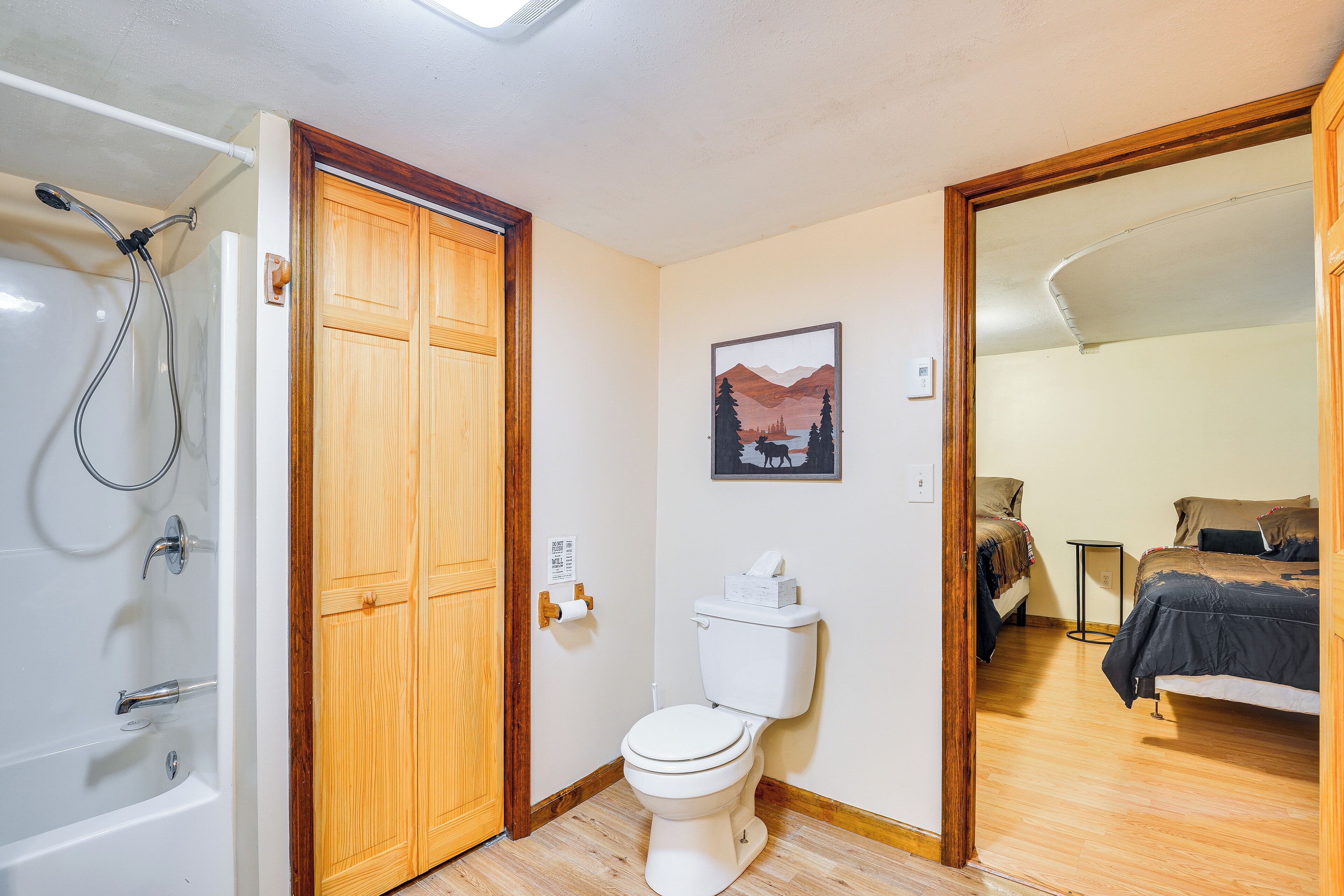 Ein Badezimmer mit Dusche, Toilette und Holztür.