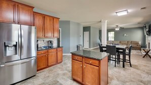 A modern kitchen with wooden cabinets, a stainless steel refrigerator, and a marble countertop.