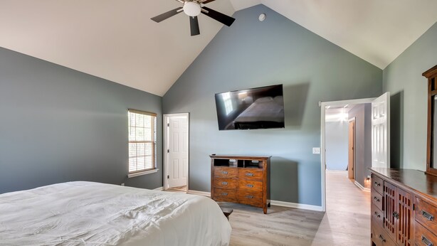 A bedroom with a bed, a dresser, a television, and a ceiling fan.