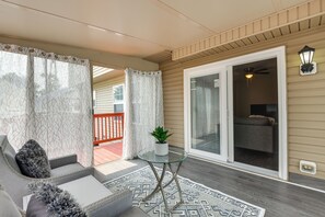 A covered porch with a glass table, a potted plant, and a patterned rug.