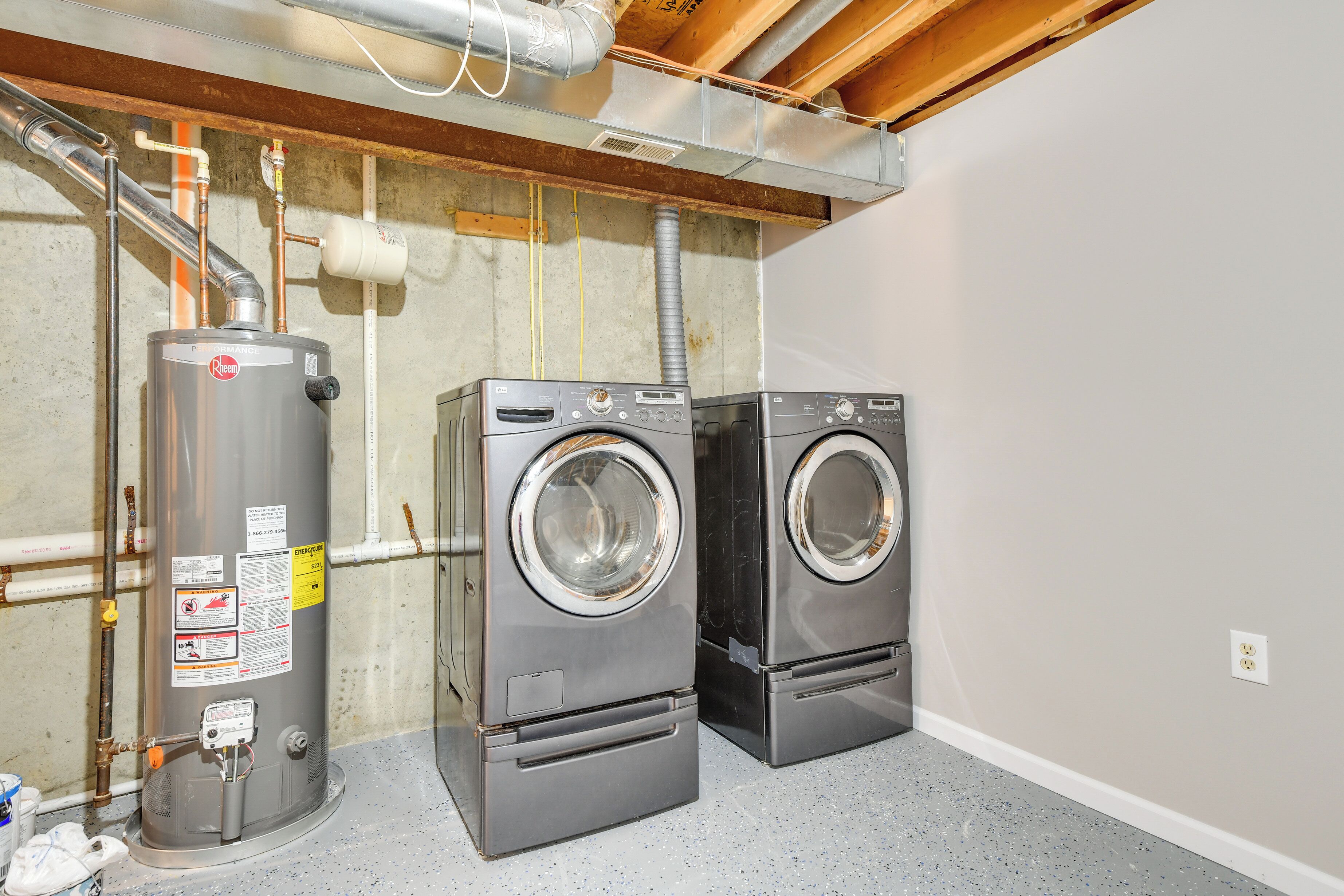 A laundry room with two front-loading washers, a water heater, and visible plumbing.