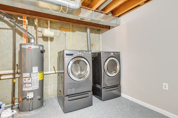 A laundry room with two front-loading washers, a water heater, and visible plumbing.
