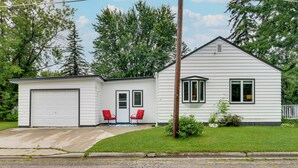 A single-story house with a garage, two red chairs outside, and a well-maintained lawn. - Downtown Baudette Vacation Rental: Walk to Dining! (Baudette)