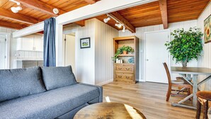 Un salon chaleureux avec un canapé gris, une table à manger en bois et une grande plante.