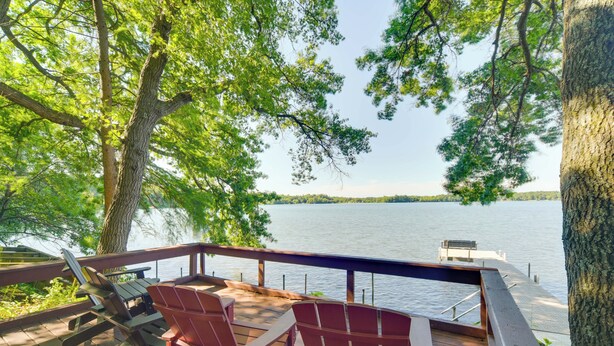 Une terrasse avec des chaises et une table donnant sur un lac.