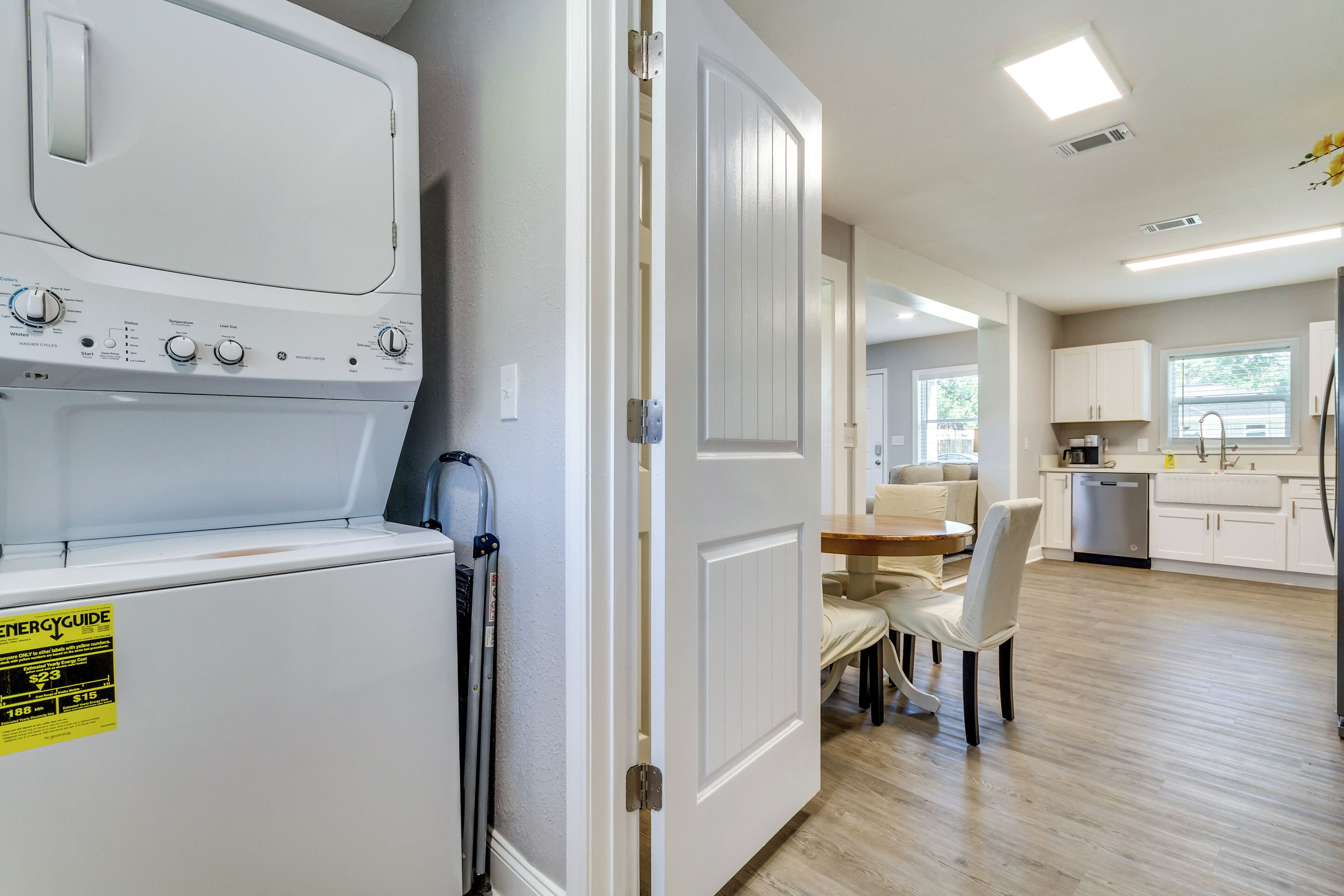A laundry area with a front-loading washer and dryer, a dining area with a table and chairs, and a kitchen with white cabinets and a dishwasher.