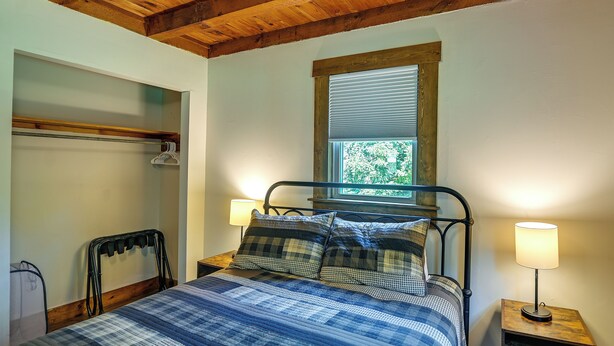 A bedroom with a bed, two bedside lamps, a window with blinds, and a wooden headboard. - Creek, Trails & Falls! Rural Red River Gorge Cabin (Campton)
