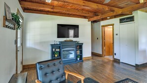 A living room with a fireplace, a television, and a black leather chair. - Creek, Trails & Falls! Rural Red River Gorge Cabin (Campton)
