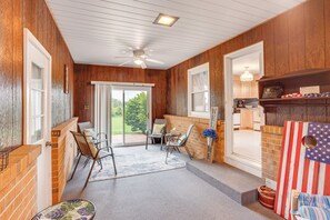 A cozy room with wooden walls, a ceiling fan, a window, and a door leading to a balcony. - 1 Mi to Hersheypark: Home w/ Patio in Hershey! (Hershey)